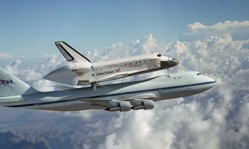 Nasa's space shuttle is being carried by a large 747 aircraft.