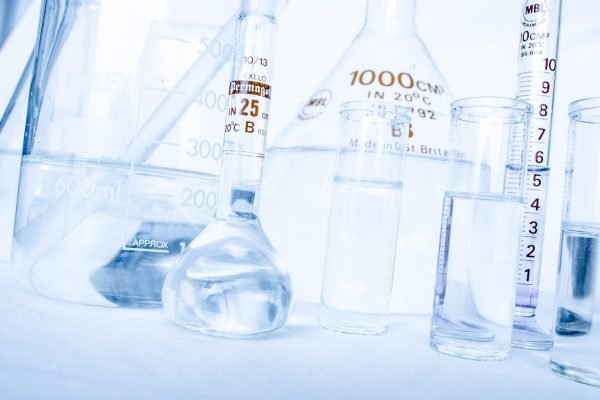 A group of test tubes and flasks containing various chemicals on a white background.