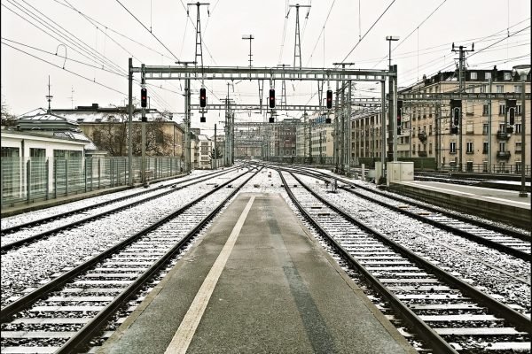 An empty train station with snow on the tracks.